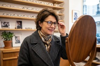 Femme française souriante essayant des lunettes dans une boutique